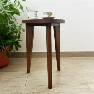 Kado ručno rađen drveni stočić od oraha sa zaobljenim gornjim delom i drvenim spojevima, prikazan u modernom enterijeru