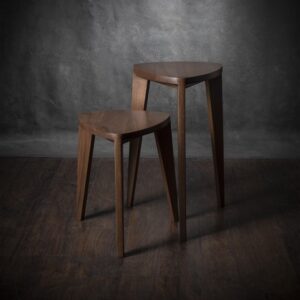 Dva ručno rađena stolčića različitih visina iz Takai seta, izrađenih od masivnog oraha, prikazani na tamnoj drvenoj podlozi.